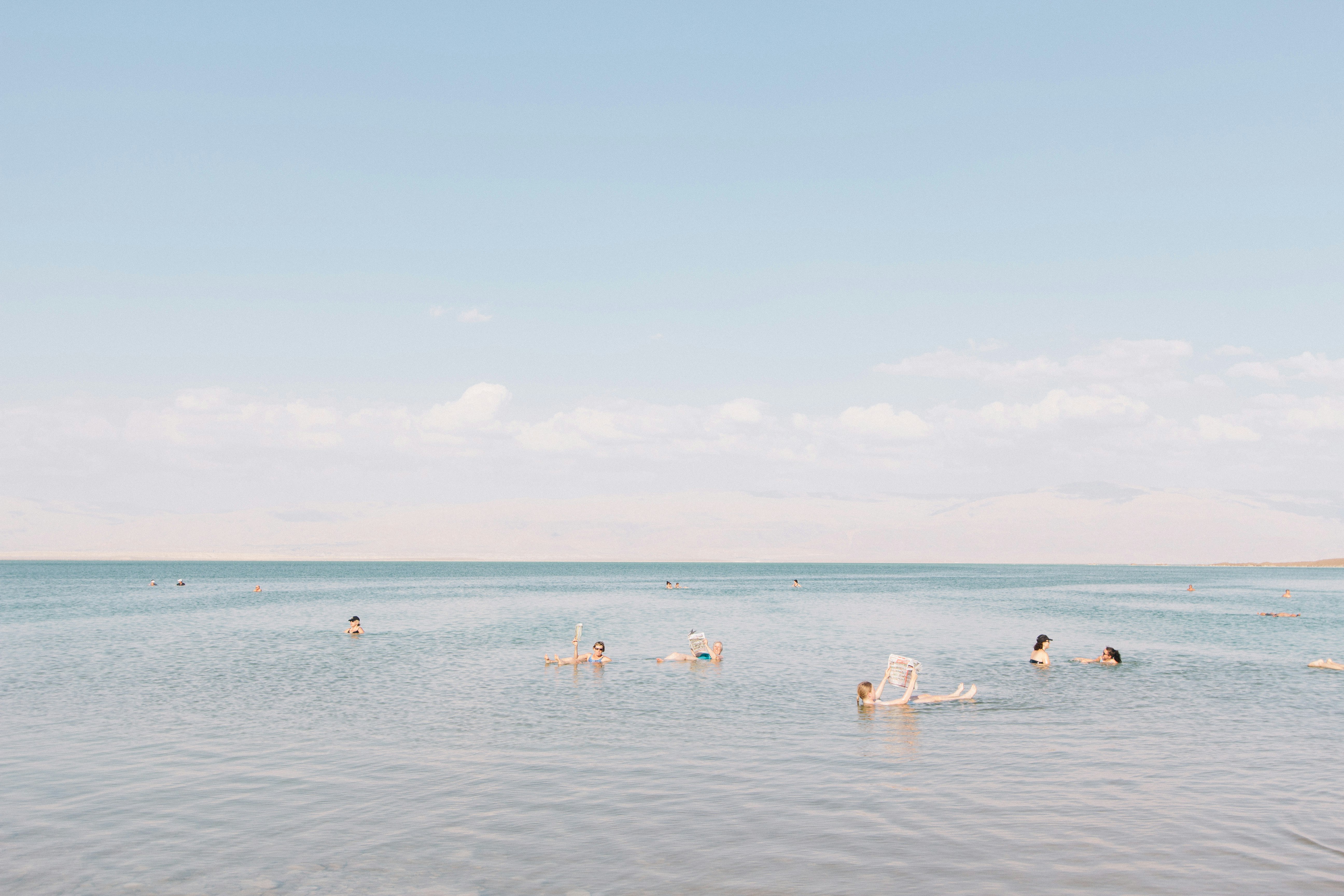 people swimming on sea under cloudy sky